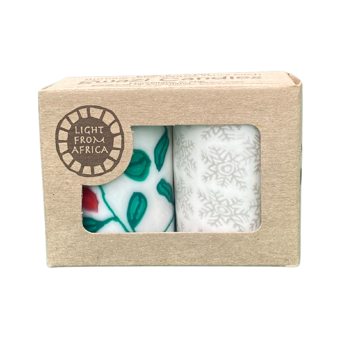 Two white candles, one with a holly and berry design, one with silver snowflakes. They are in a craft box that says 'Light from Africa' and Swazi Candles is on the top of the box.