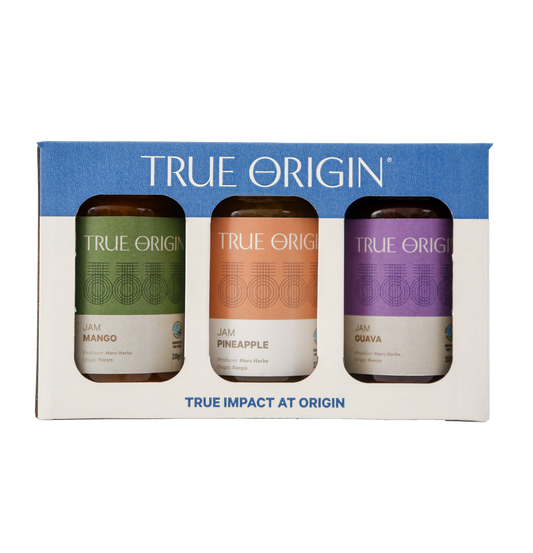 A gift set box containing three jars of True Origin brand jams: Guava Jam, Pineapple Jam, and Mango Jam, each with a clear label showing the flavor and 'True Impact at Origin' text.