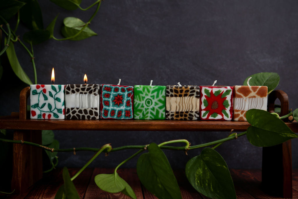 Set of candles with different patterns on a wooden stand against a dark background