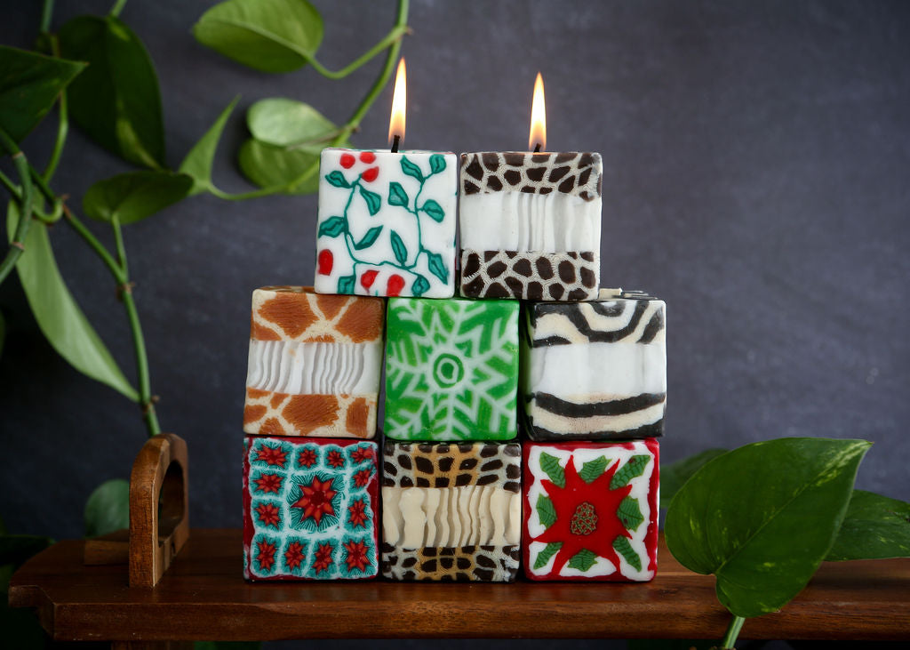 Stack of patterned lit candles on a dark background