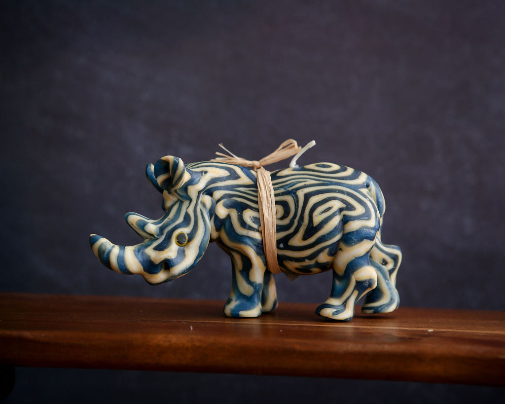 Decorative ceramic rhino candle with blue and white patterns on a wooden surface.