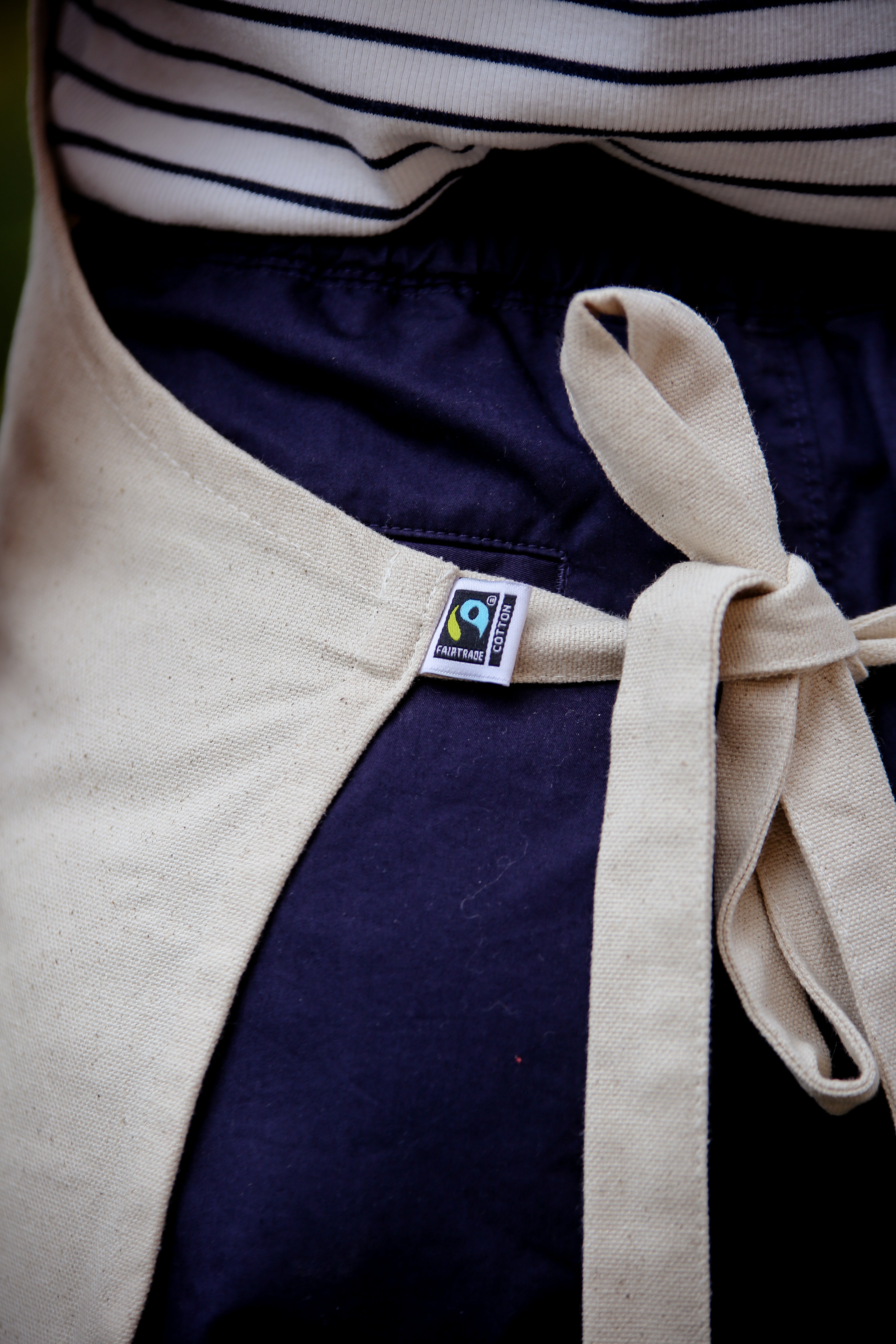 Fairtrade cotton beige apron which is tied behind someone's back to show the Fairtrade logo.