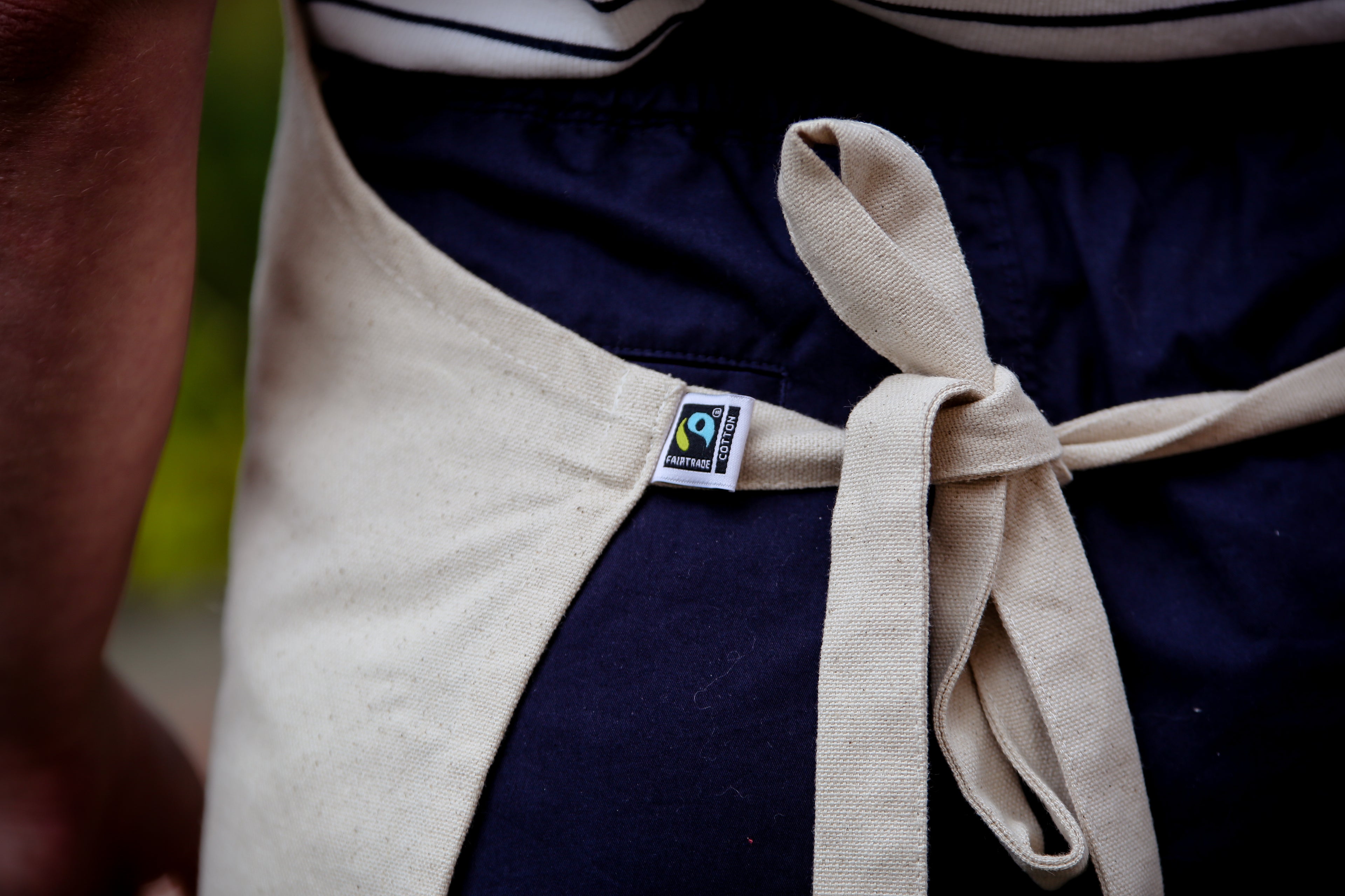 Fairtrade cotton beige apron which is tied behind someone's back to show the Fairtrade logo.