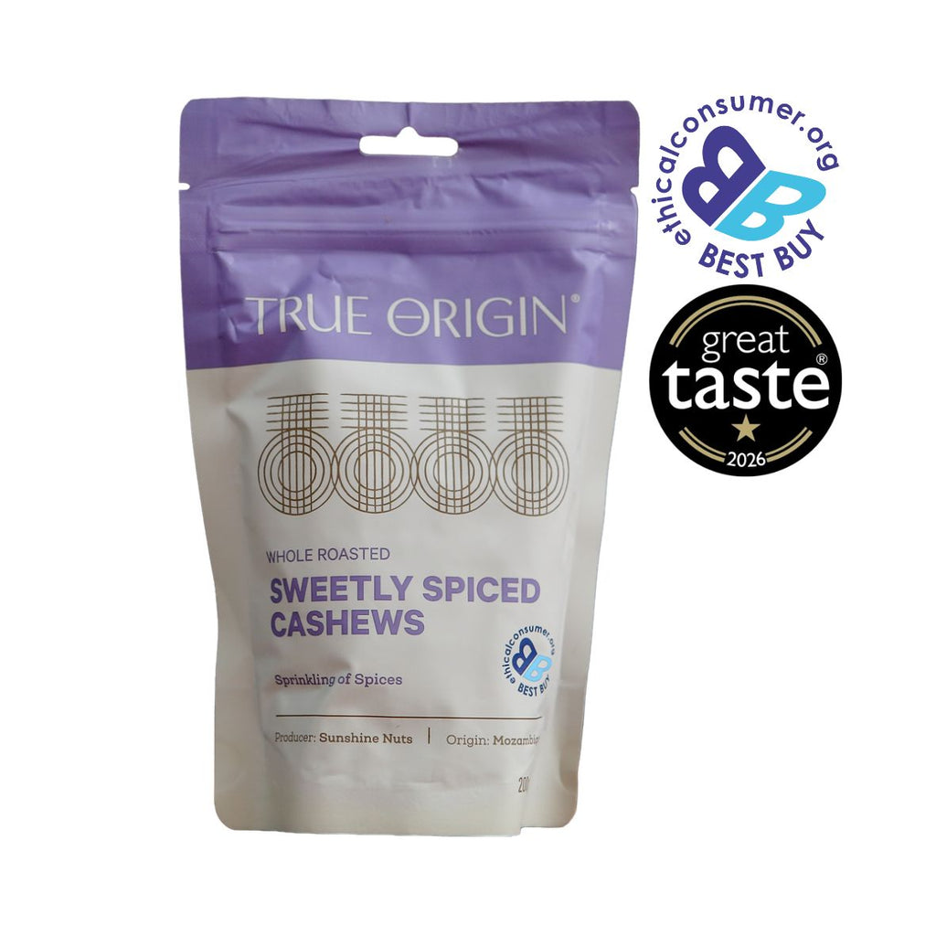 A stand-up pouch of True Origin Sweetly Spiced Cashews on a white background, with a purple top section and cream lower section. Two award badges are displayed on the top right: The Best Buy Logo and 1 star Great Taste Award 2026.