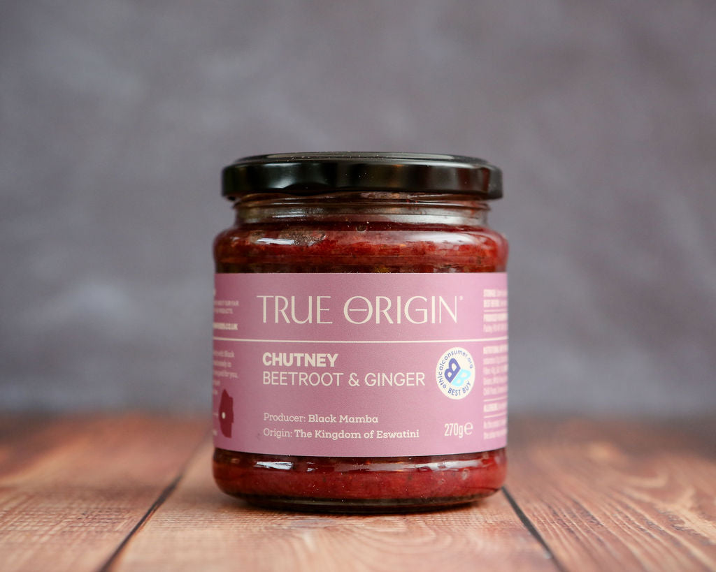 Jar of True Origin chutney on a wooden surface with a gray background
