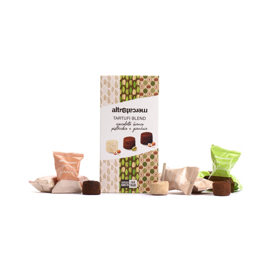 A box of assorted chocolate and nut truffles with several individually wrapped truffles displayed in front. The packaging has a patterned design and indicates the product is made with Fair Trade ingredients.