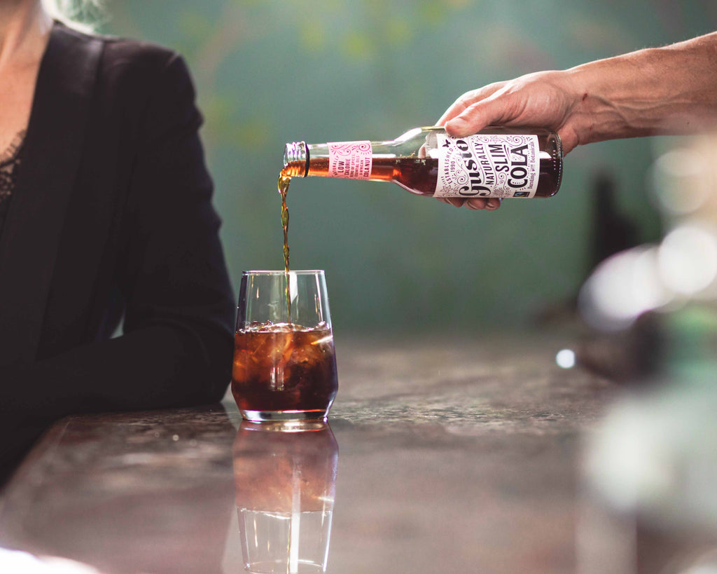 Gusto Organic Naturally Slim Cola being poured into a glass with ice