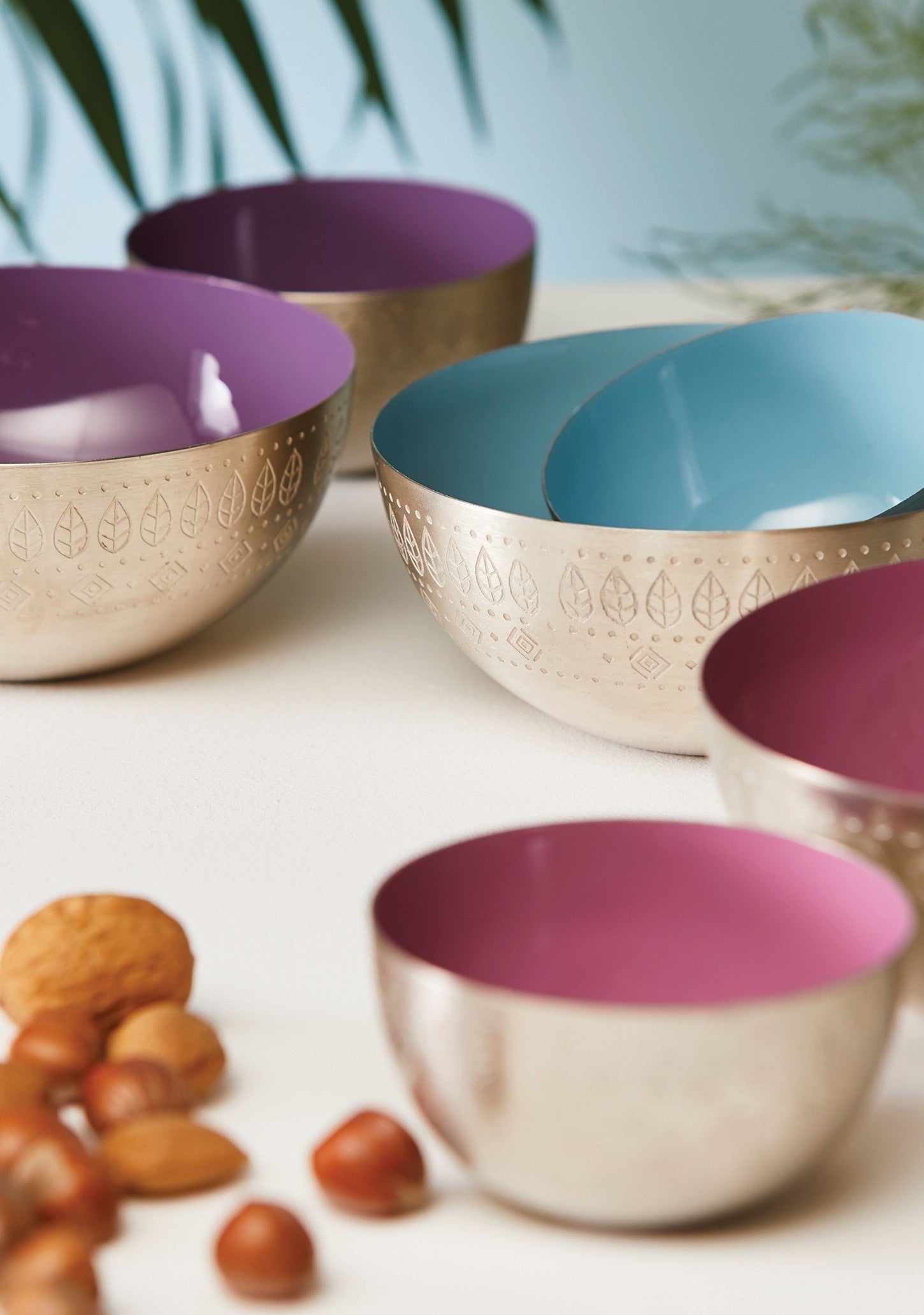 A set of enamel bowls with purple, pink and blue on the inside and they are silver with an etched pattern on the outside.