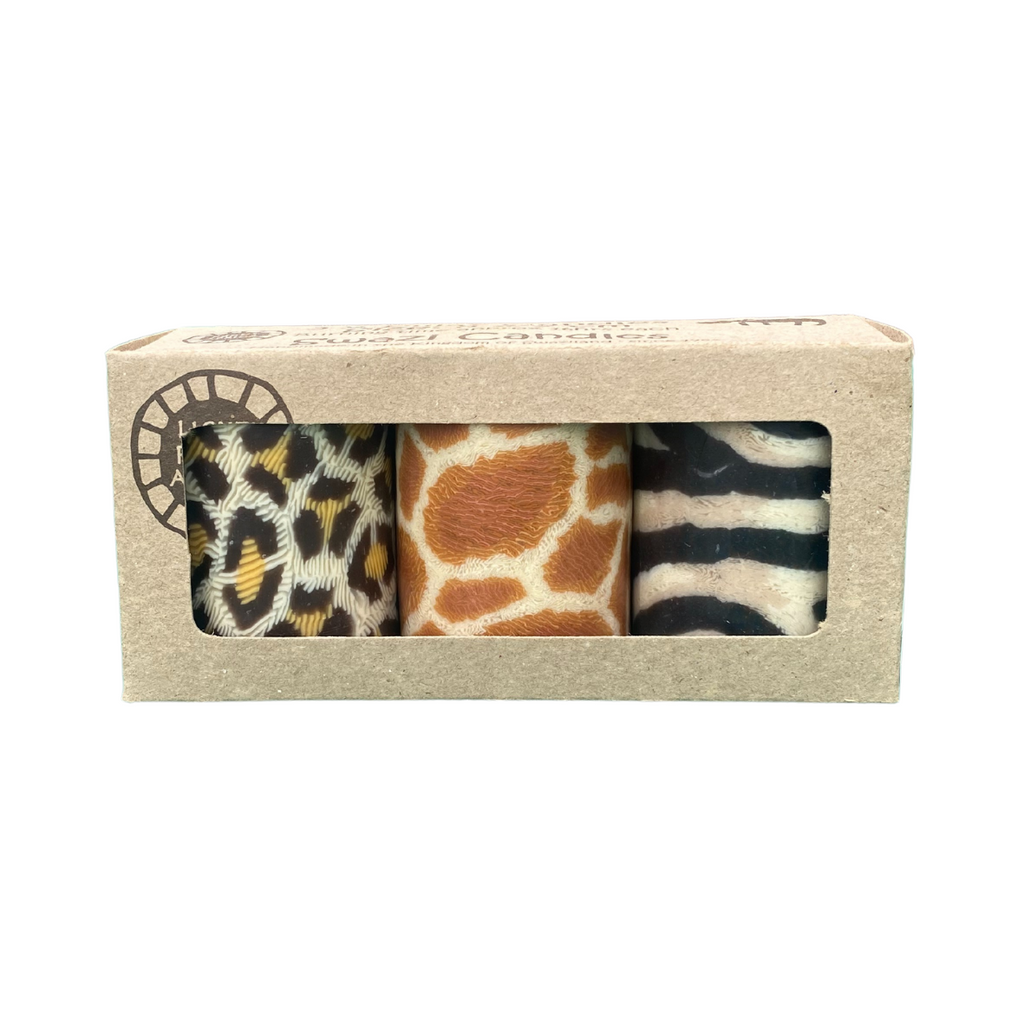 A triple pack of hand crafted Swazi church candles with 3 different animal print designs, there is leopard, giraffe and zebra print.  They are in a craft box on a white background.