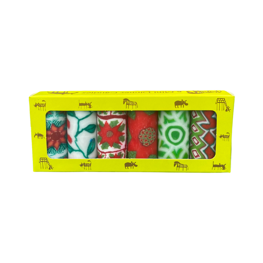 A pack of 6 Swazi candles, each with a different Christmas design in white, green and red colours.  They are in a yellow box with African animals on it on a white background.
