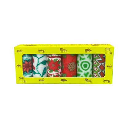 A pack of 6 Swazi candles, each with a different Christmas design in white, green and red colours.  They are in a yellow box with African animals on it on a white background.