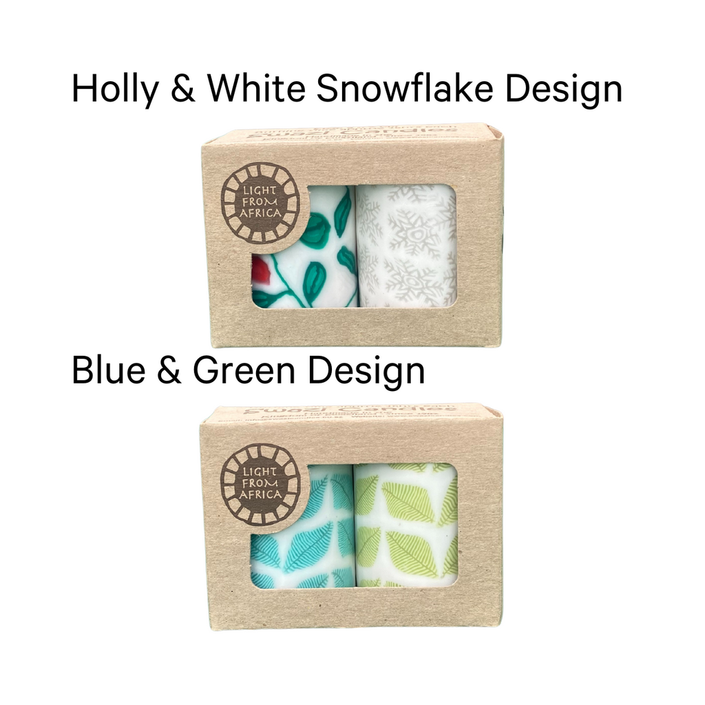 Two duo packs of swazi candles, one with holly and snowflake design, one with a blue and green fern leaf design.  Both are in a craft box on a white background.