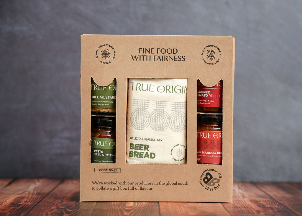Gift set with True Origin products in a cardboard box on a wooden surface with a gray background