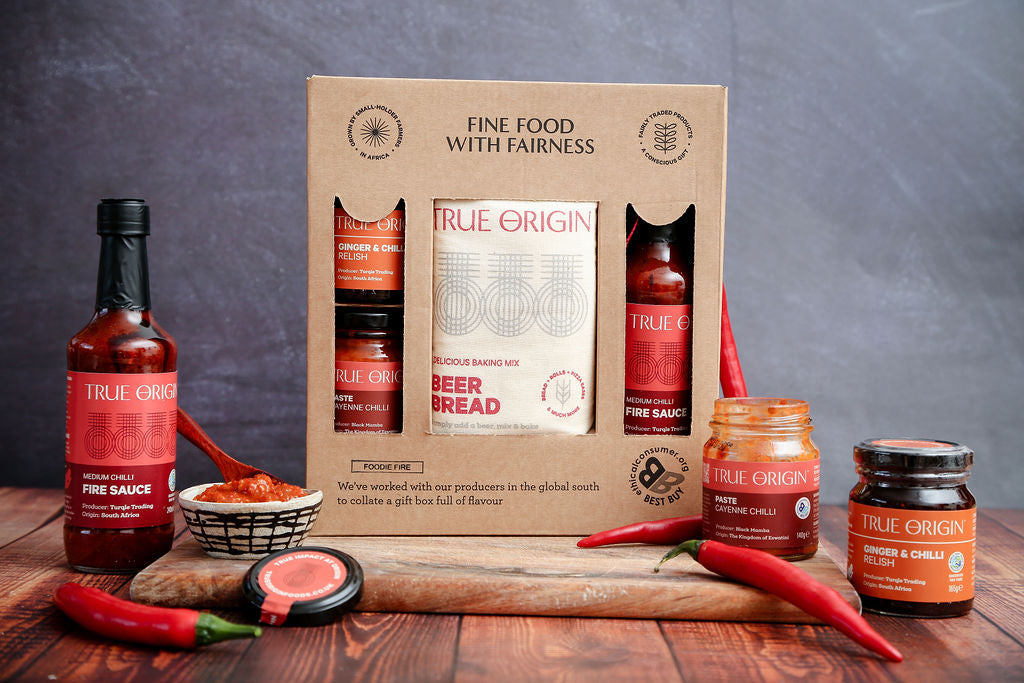 True Origin food products including sauces and a box on a wooden table with a dark background