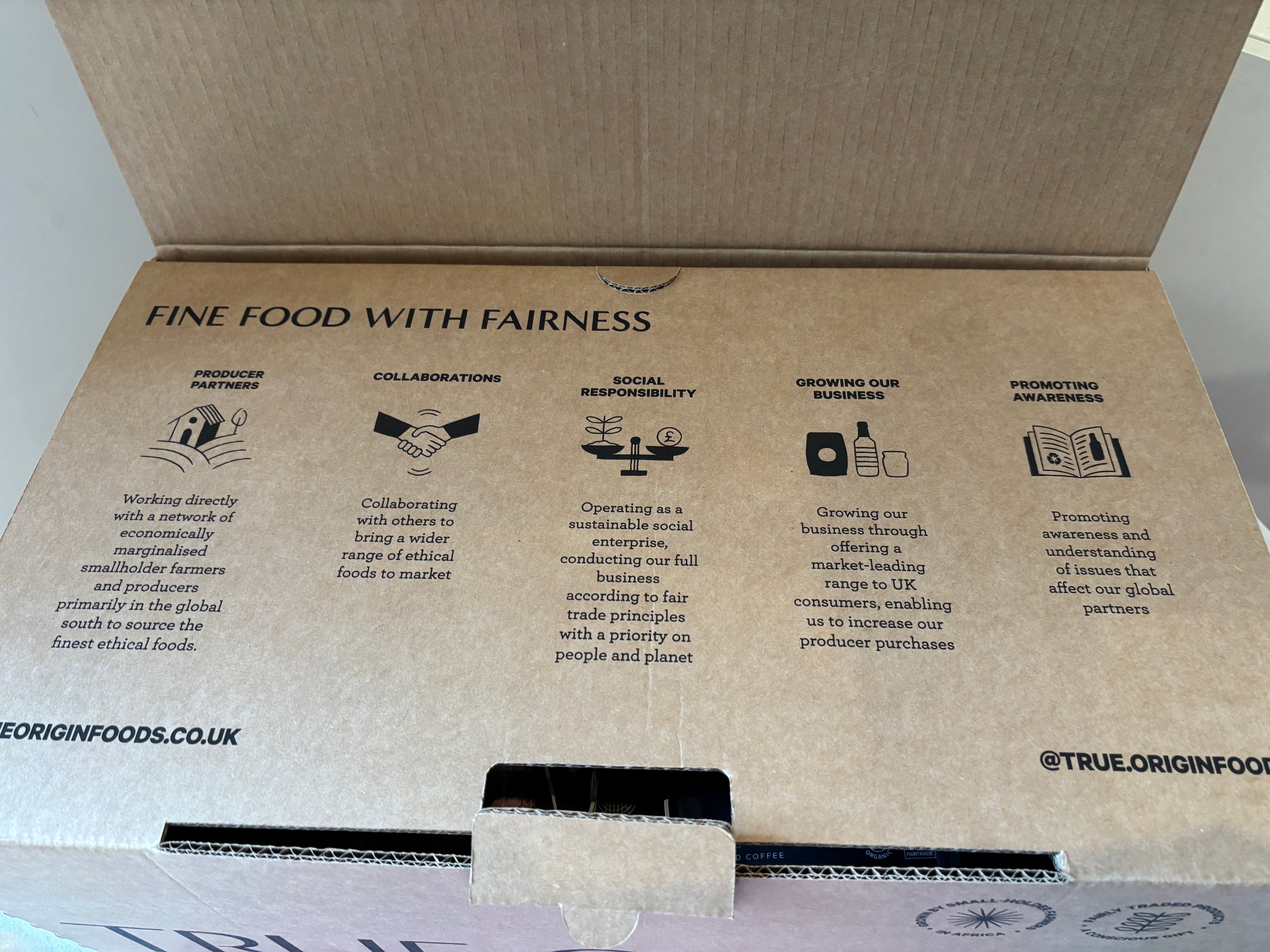Cardboard hamper box with 'True Origin Foods' branding, goals, and missions on a white background