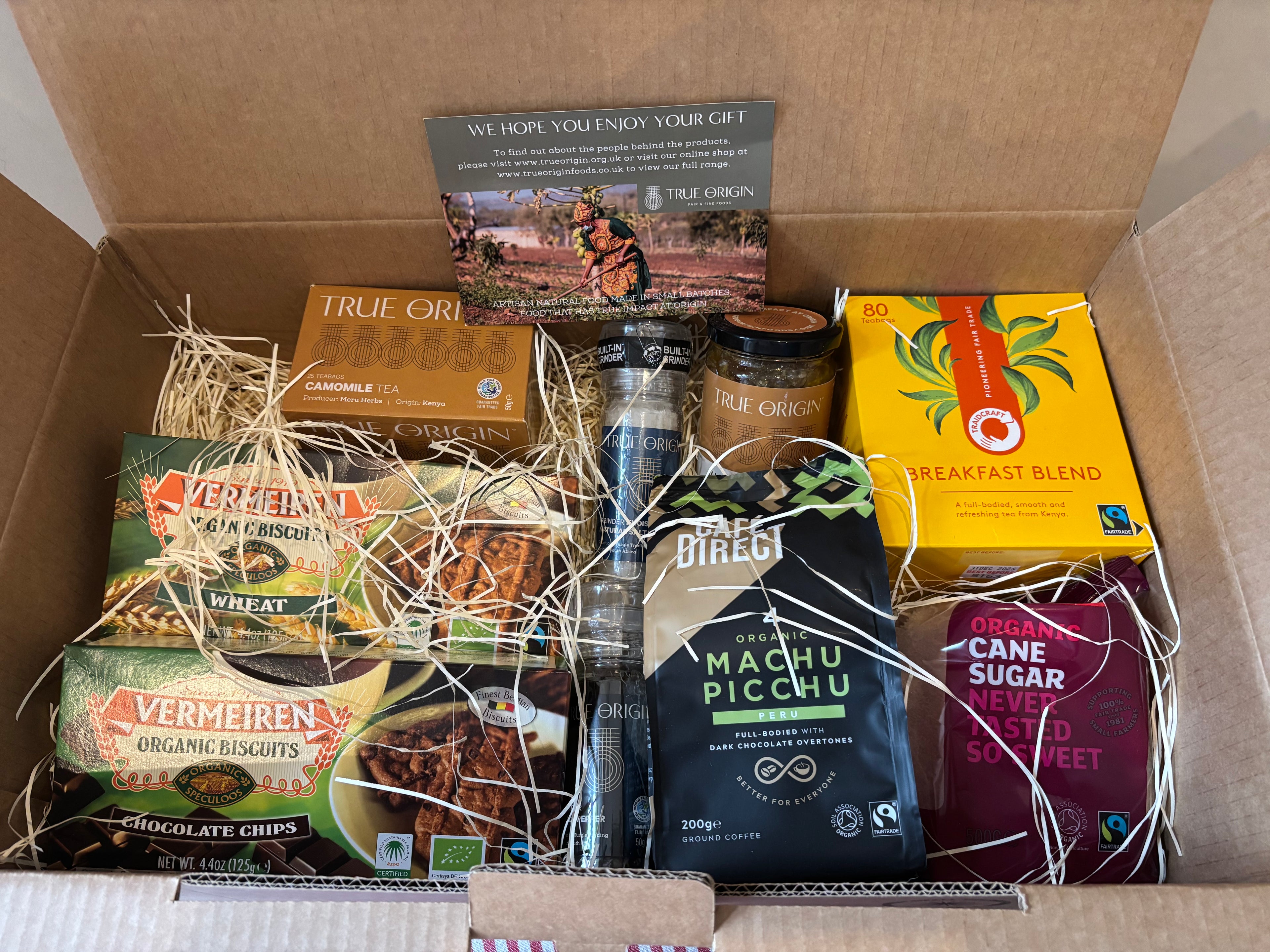 Box of assorted food items including coffee, cookies, and other packaged goods, all contained within the Essentials Selection Hamper.