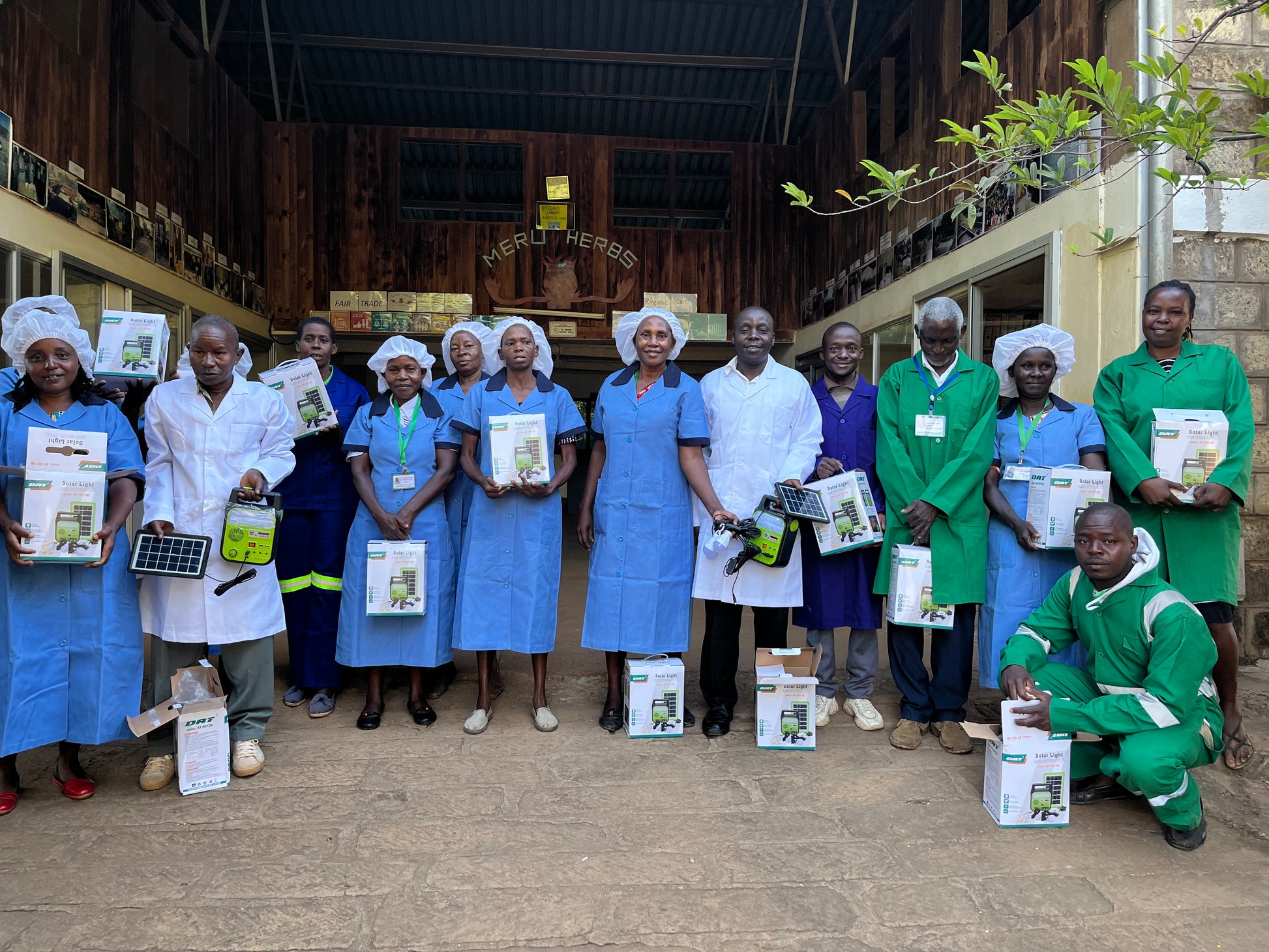 Group of workers in the Meru Herbs factory in Kenya holding boxes with solar panels.