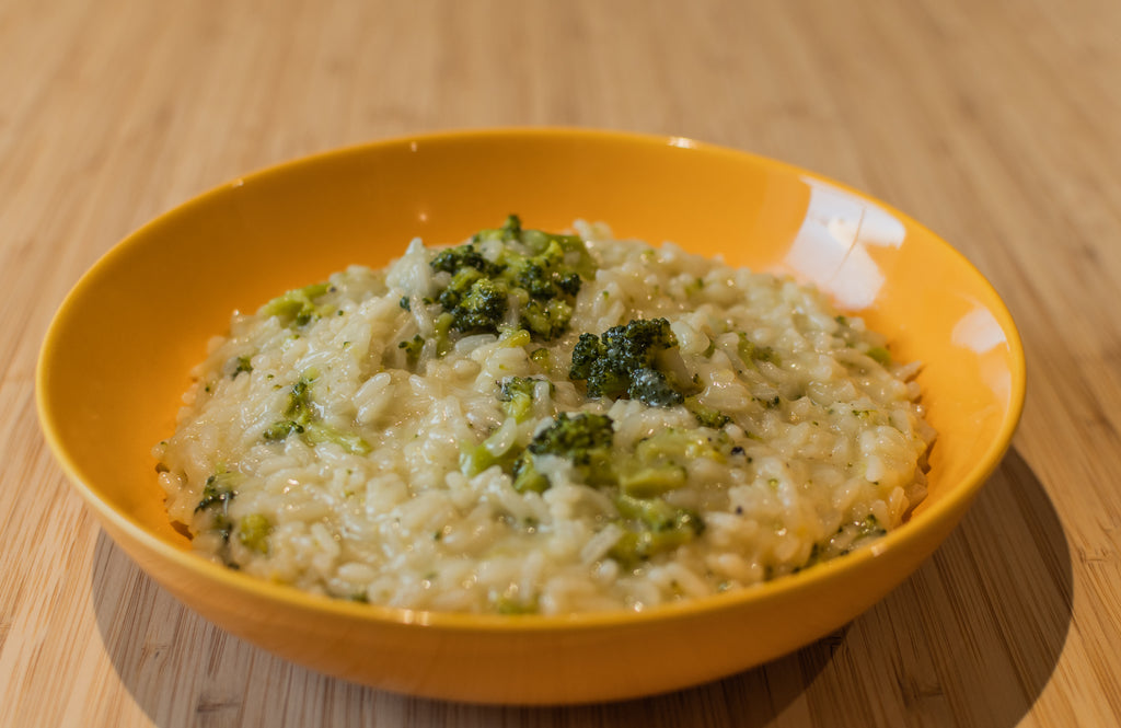 A yellow bowl with some freshly cooked broccoli and lemon risotto using Kilombero rice.