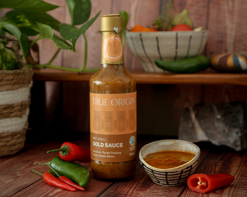 A bottle of True Origin Gold Hot Chilli Sauce with a two tone brown label.