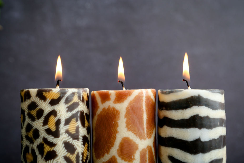 Three candles with animal print designs on a dark background