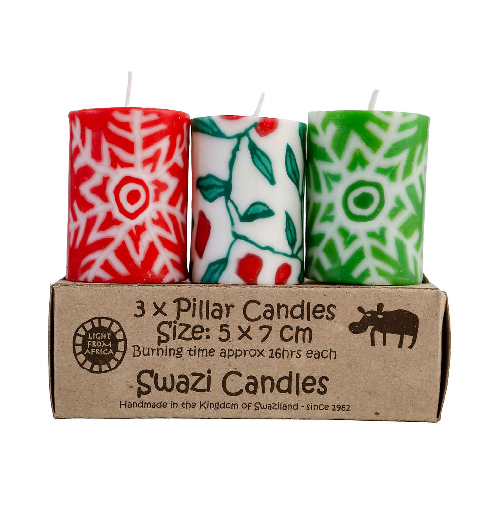 Three patterned Christmas candles in a cardboard box with 'Swazi Candles' branding.