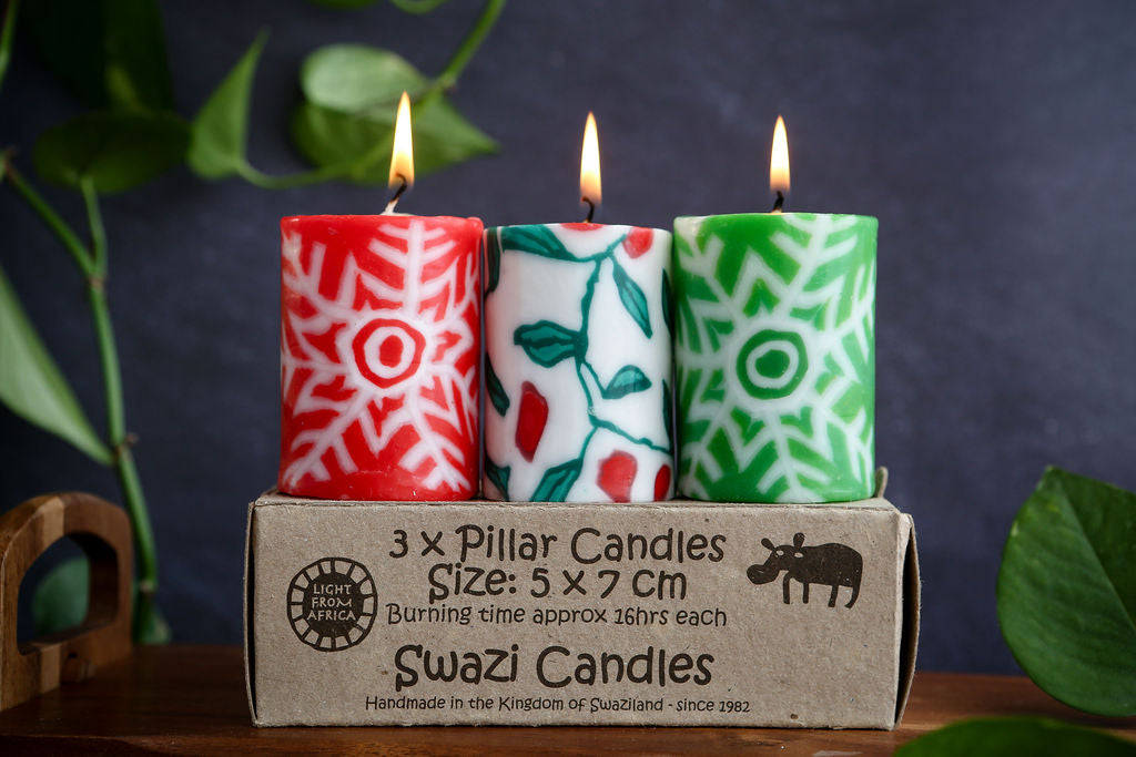 Three patterned candles in a cardboard box with 'Swazi Candles' branding.