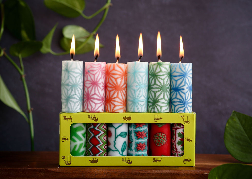 Colourful candles with floral patterns in a box against a dark background