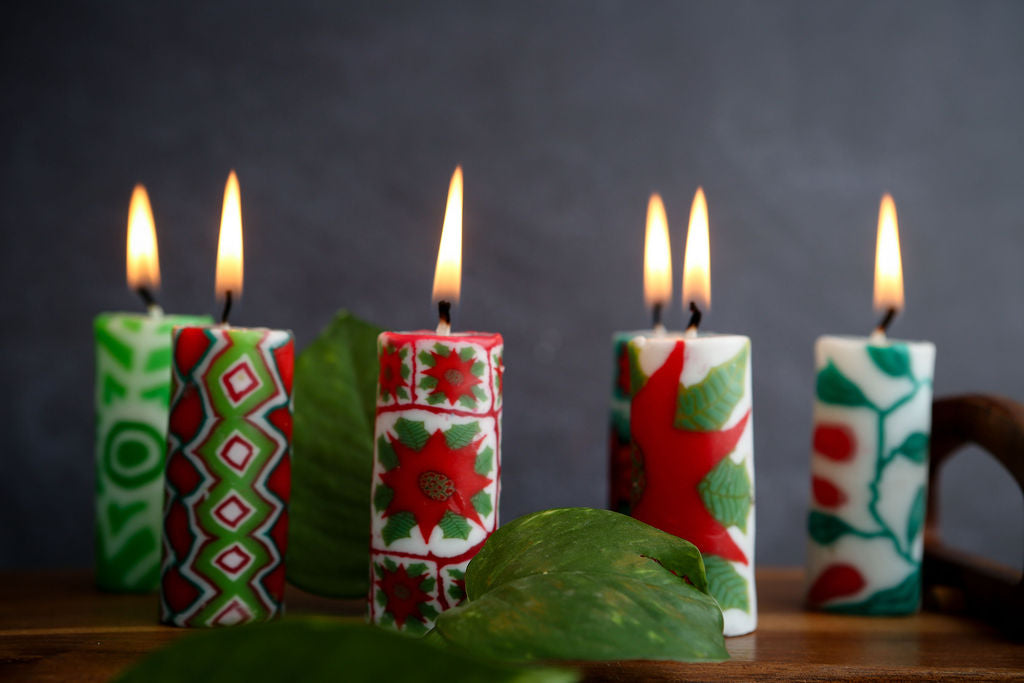 Decorative lit christmas design candles with green leaves on a dark background