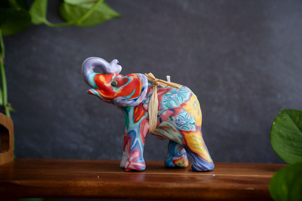 Colourful elephant handmade candle on a wooden surface with a dark background