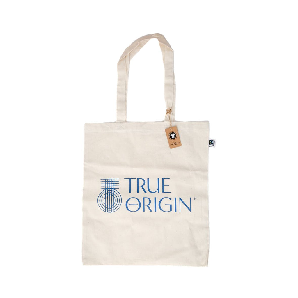 A cream Fairtrade cotton tote bag with the blue stacked True Origin logo with some True Origin products sticking out the top.